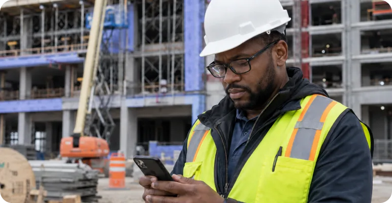 Construction professional checking their phone on site