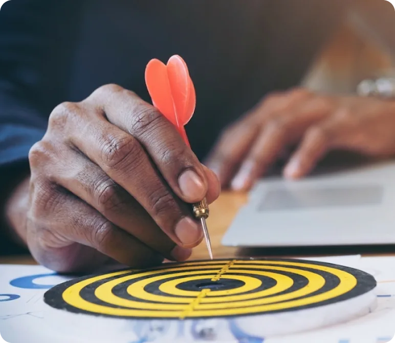 Hand placing a dart in the centre of a target