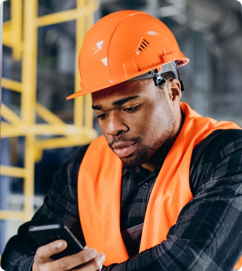 Construction worker in an orange helmet using a phone