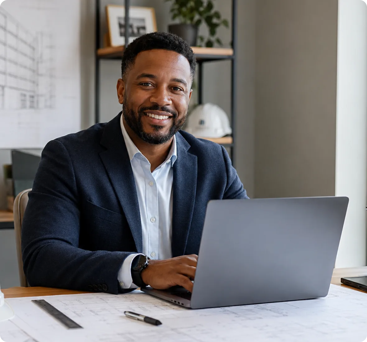 Professional working at a laptop over building drawings